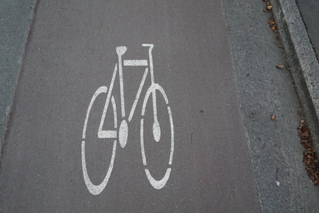 A white bicycle symbol painted on an asphalt bike lane, indicating a designated cycling path.