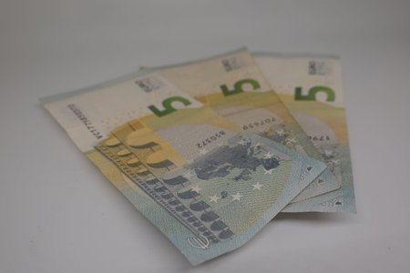 Three 5 euro banknotes lying on a white background represent savings, income, or investment
