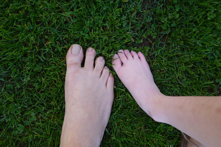 Barefoot adult and child feet are touching the soft green grass, enjoying a moment of connection...