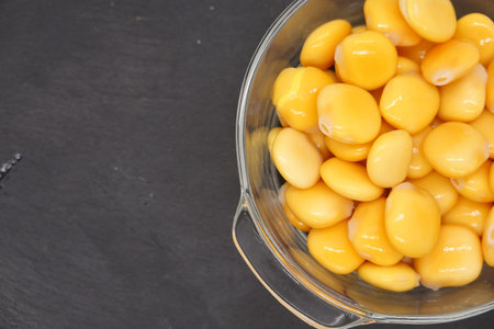 Glass bowl full of lupine beans on dark background, ready to be eaten as a healthy snack or...