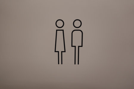Simple black and white male and female restroom symbols on a plain wall provide clear gender identificationの写真素材