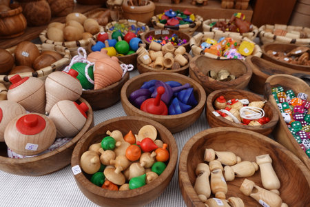 Wooden toys, traditional spinning tops, and colorful dice for sale in a market stall, promoting sustainable play and craftsmanshipの写真素材