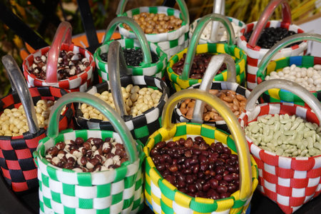 Variety of different colored dried beans and legumes filling small, woven plastic baskets,...