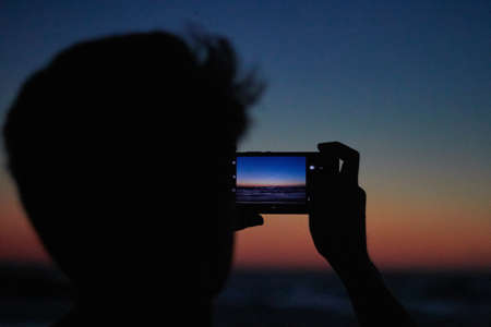 Friends with cellphone in beachの写真素材