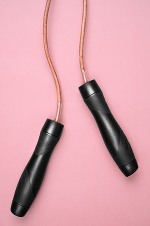 close-up wooden handles of skipping rope isolated on pink backgroundの写真素材
