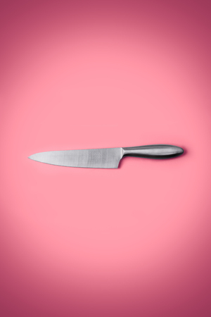 Stainless steel kitchen knife isolated over pink background,の写真素材