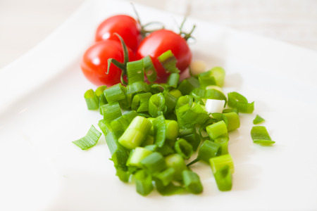 cropped leek lies with tomates on a plateの写真素材