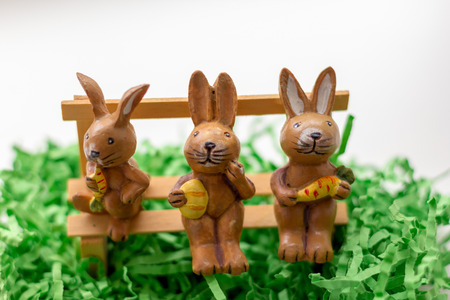 decoration rabbits sitting on a bench near a windowの写真素材