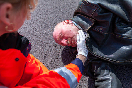 A german paramedic check blood pressure on an injured bikerの写真素材