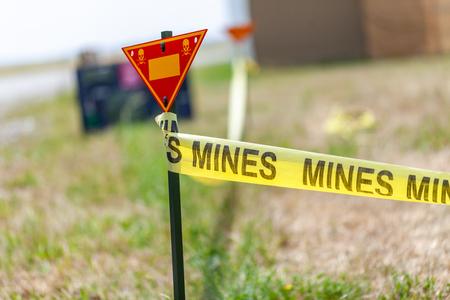 land mine warning sign stands on grassの写真素材