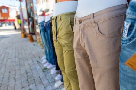 Various trousers weared by model dolls in front of a pants shopの写真素材