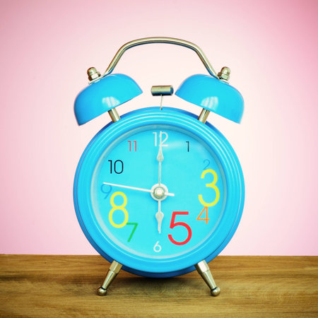 Alarm clock put on the wooden in pink wallpaper room 