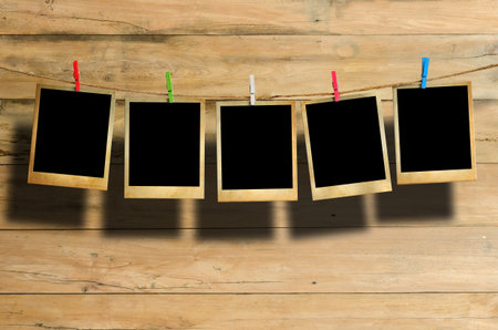 Old picture frame hanging on clothesline on wood background.の写真素材