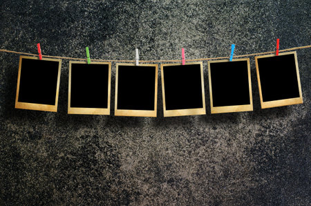 Old picture frame hanging on clothesline on grunge wall.