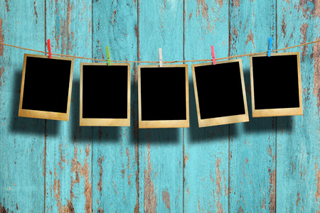 Old picture frame hanging on clothesline on wood background.の写真素材