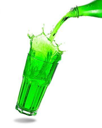 Pouring green soda from bottle into glass with splashing isolated on white background.の写真素材