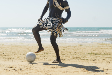 black man on the beach playing footballの写真素材