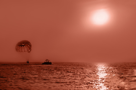 Happy couple flying on a parachute on a sunset backgroundの写真素材