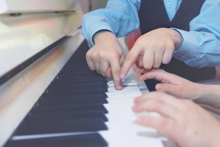 guy and the girl play both on the piano in four hands, close upの写真素材