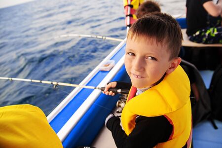 little boy fishing with a spinning boat from a boat.の写真素材