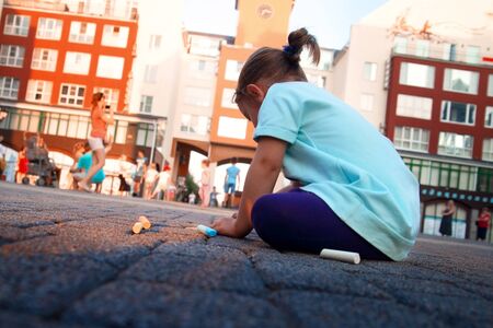 child draws with chalk on the pavement.の写真素材