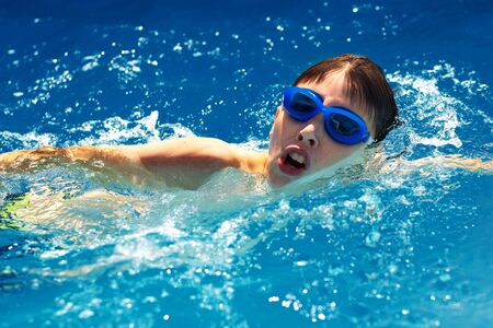 Little boy athlete swims in the pool by the crawl. The concept of training and childrens sportsの写真素材
