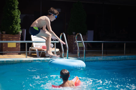 Blured image of child jumping at swimming pool party - Vacation concept with happy friends having...