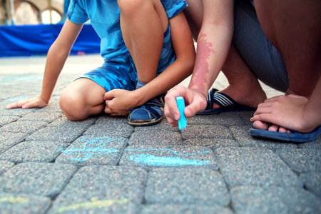 Two boys draw with chalk on the pavement. The concept of a happy childhood