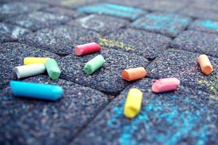 Colorful pastel sidewalk chalk on dark asphalt background. Colorful children's crayons on the asphalt close up. The concept of development of children's creativityの写真素材
