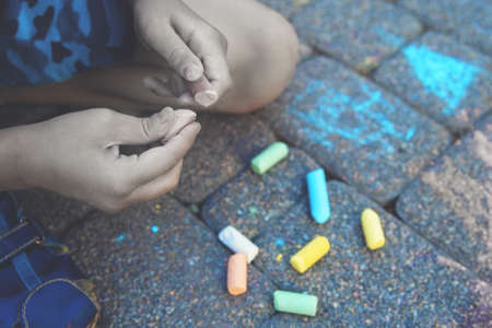 Little lonely sad boy sits on the asphalt and draws with chalk. Sadness and loneliness conceptのeditorial素材