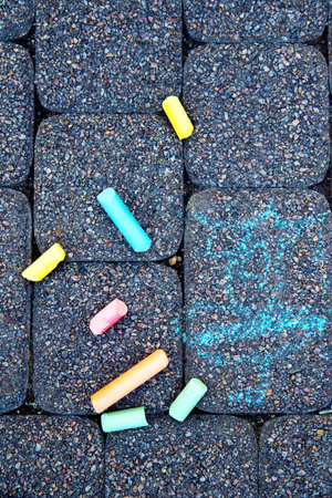 A childs drawing and colorful chalks on a street, a sidewalk or a pavement. Childrens drawing with...