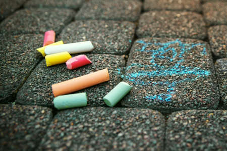 Blurred image Colorful pastel sidewalk chalk on dark asphalt background. Colorful children's crayons on the asphalt close up. The concept of development of children's creativity. Blurred image, selective focus. No focusの写真素材