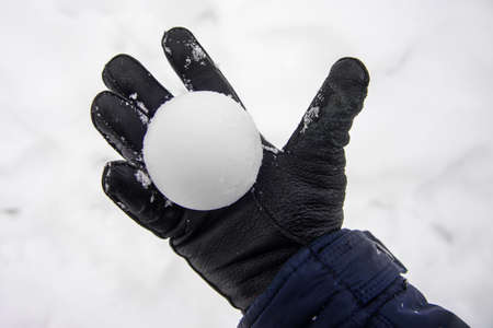 snowball in hand. a hand in a glove holds a snowballの写真素材