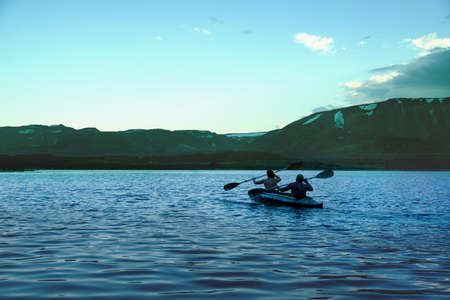 A man and a woman are canoeing on a mountain lake. Beautiful landscape of a mountain lake in Norilsk, Taimyrの写真素材