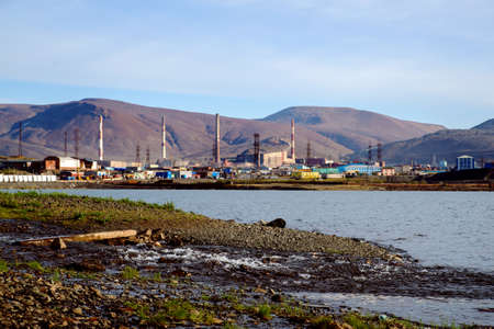 The shore of a polluted lake against the backdrop of a metallurgical plant in the city of Norilskの写真素材
