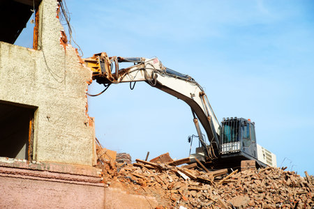 excavator demolishing a brick building. Machinery Demolishing Building.の写真素材