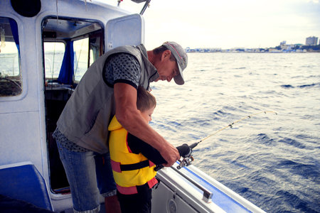 ANAPA, RUSSIA -JULY 21, 2019: dad with son fishing on a boat.のeditorial素材