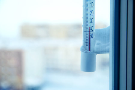 Classic mercury thermometer for measuring ambient temperature, hanging outside the window, with...