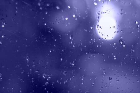 Rain drops with bokeh effect in the night city. Drops of rain on window with abstract lightsの写真素材