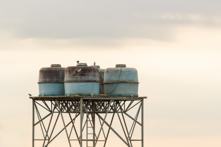 old water tanks on high stand under cloud skyの写真素材