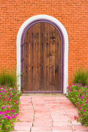 wooden door on brick texture with flowers infront of walking pathの写真素材