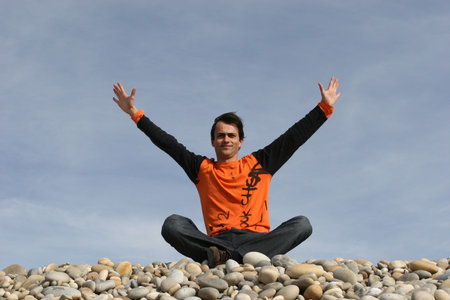 young casual man with arms wide open at the beachの写真素材