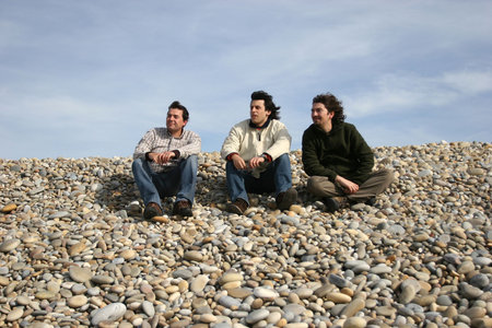 three casual young men at the beach isolated in blue sky backgroundの写真素材