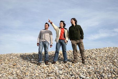 three casual young men at the beach, isolated on blue backgroundの写真素材