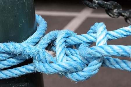Detail of a blue rope, tied to a pole, at the dockの写真素材