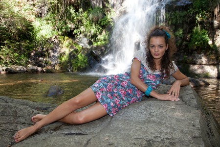Beautiful woman posing near a waterfallの写真素材