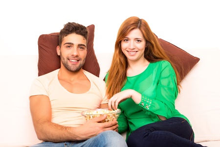 Young couple watching something on the television in the couchの写真素材