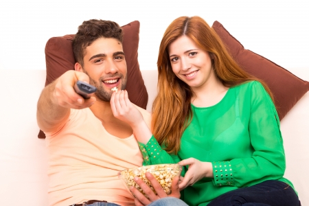Young couple watching something on the television in the couchの写真素材