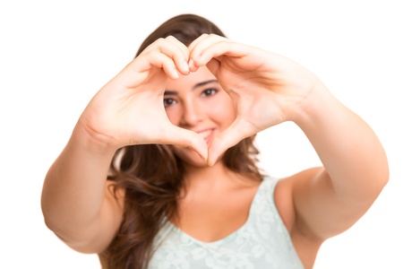 Beautiful woman making a heart shape with her hands, isolated over white backgroundの写真素材