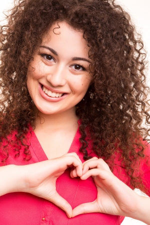 Beautiful woman making a heart shape with her hands, isolated over white backgroundの写真素材